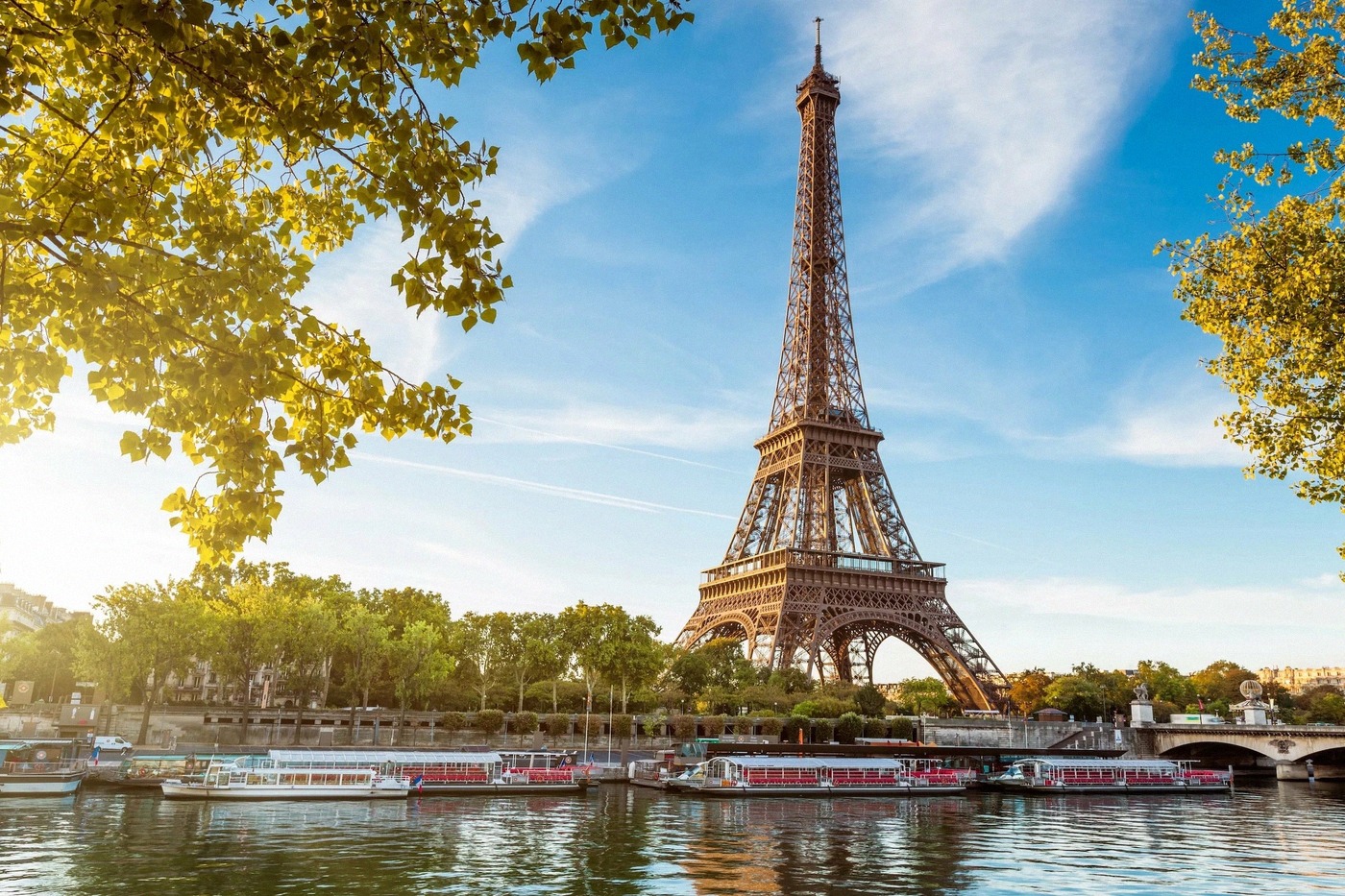A classic shot of the Eiffel Tower from the Seine in the warm morning light, with a tour boat on the
