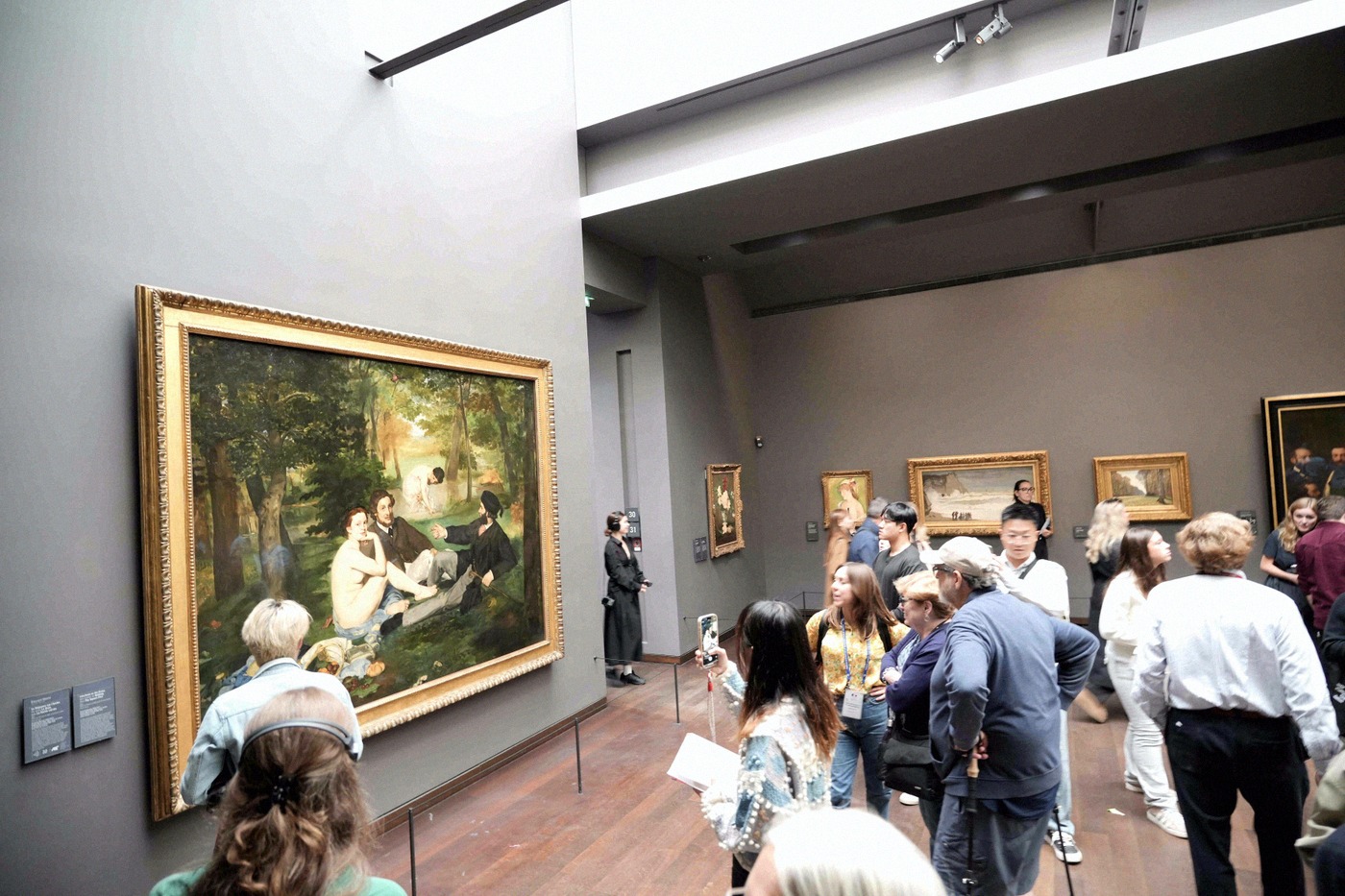 Visitors look at Édouard Manet's large-scale painting "Le Déjeuner sur l'herbe" in a room of the Musée